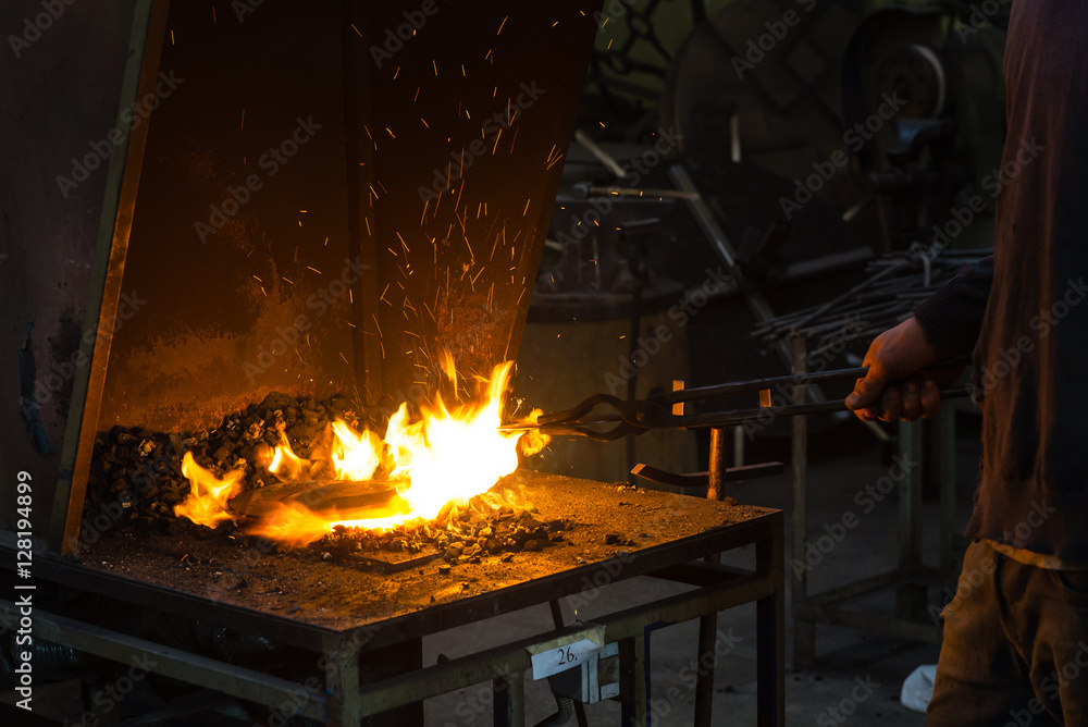 The blacksmith making flames in smithy