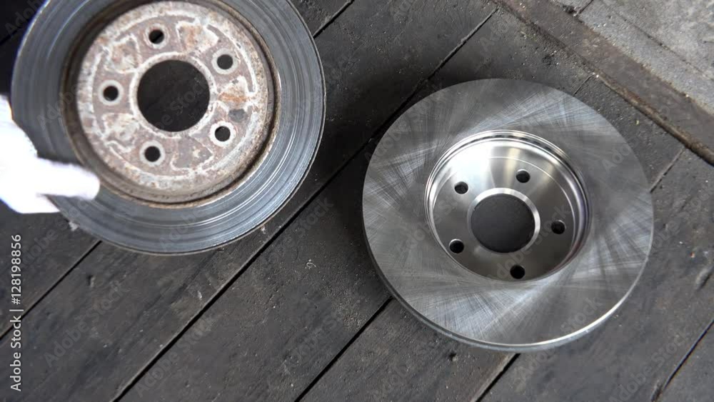 hand showing bad worn brake disk with contrast to new one on wooden floor. hand showing bad worn brake disk with contrast to new one on wooden floor.