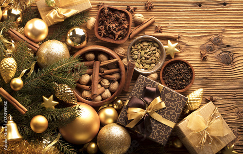 Christmas theme, christmas decoration. presents in boxes on a wooden table with golden baubles, clove, cardamon, star anise, cinnamon. Golden and brownish aesthetics. Place for typography and logo. © zolnierek