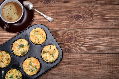 Breakfast egg muffins with broccoli and cheese. Cup of coffee.