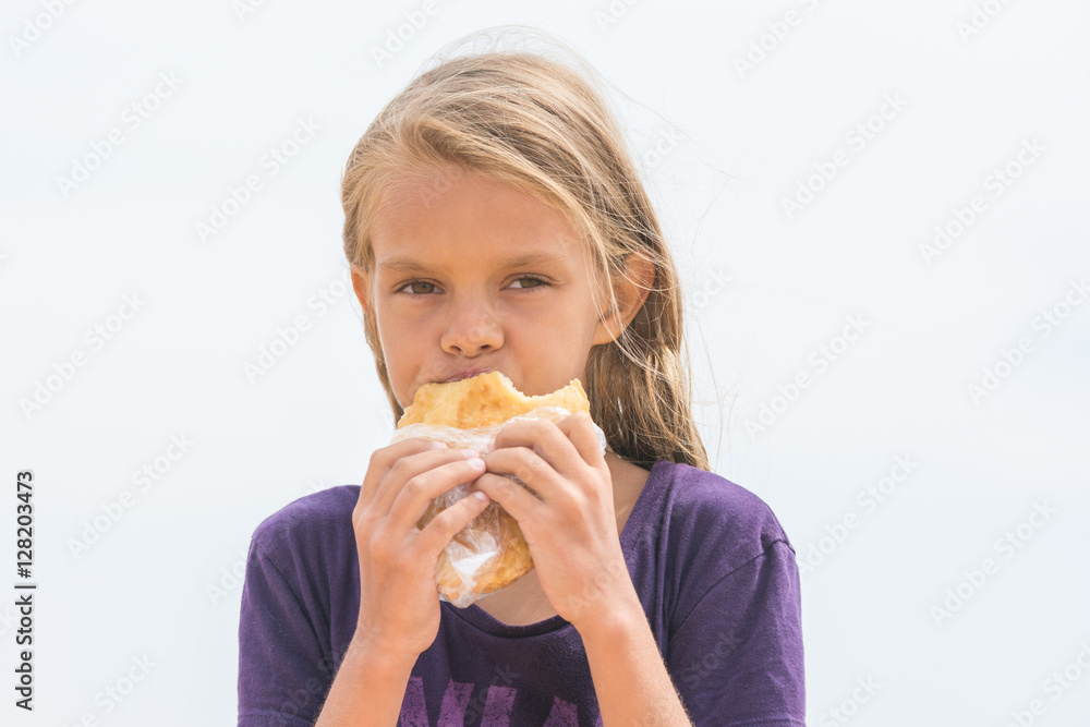 A hungry girl with an appetite chews delicious cake and looked into the frame