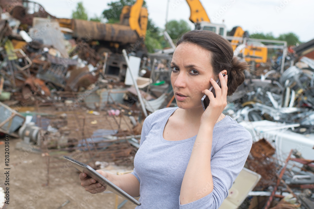Woman in scrap yard using mobile phone Woman in scrap yard using mobile phone