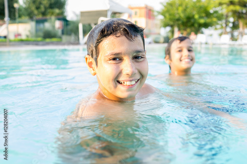 Young boy kid child splashing in swimming pool having fun leisur