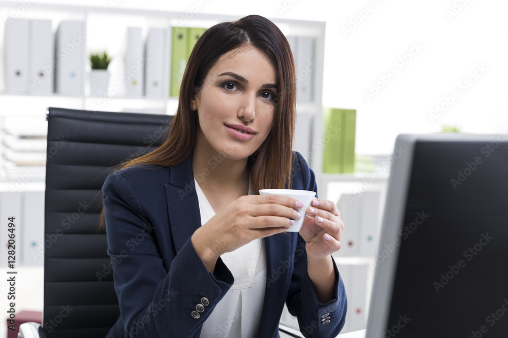Smiling and nostalgic businesswoman with a cup of coffee in an o Smiling and nostalgic businesswoman with a cup of coffee in an o
