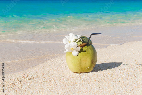 Fresh coconut juice with straw and Plumeria flowers on the tropi