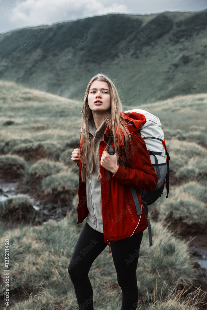Shot of a young woman looking at the landscape while hiking in the mountains.Outdoor shot of attractive young woman with backpack standing in a mountain stream. Female hiker in creek water.