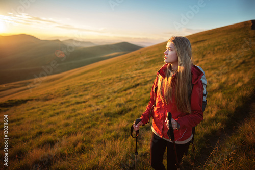 Shot of a young woman looking at the landscape while hiking in the mountains. Young tourist with backpack relaxing and enjoying sunset.