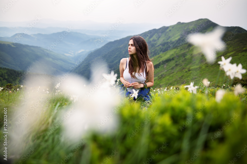 Shot of a young woman looking at the landscape while hiking in the mountains. Female hiker hiking in the mountain. Hiking trail with flowers
