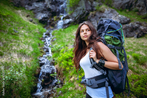 Portrait of a beautiful young woman standing in a mountains with a waterfall in the background