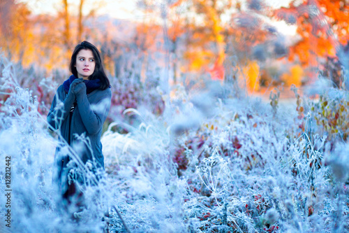 Beautiful sunrise with frost. Portrait of a beautiful girl freezing in the winter forest. Woman in boho style.