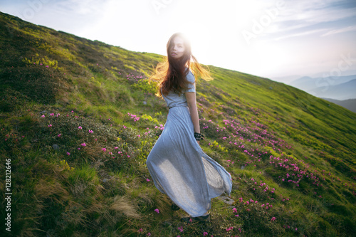 Young woman in a dress running to the sun in the mountains. Young girl in the mountains. Defocus