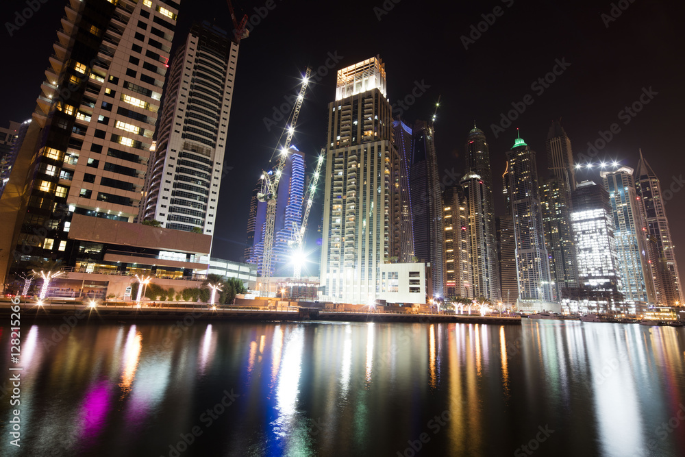 Obraz premium Architecture theme. Dubai marina. Luxurious travel and living, business and finance theme. Luxurious apartments. High value property. Night lights. Illuminated skyline. Big construction site.