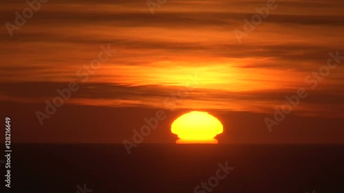 Sunset time lapse close up of sun setting on mostly clear night.
