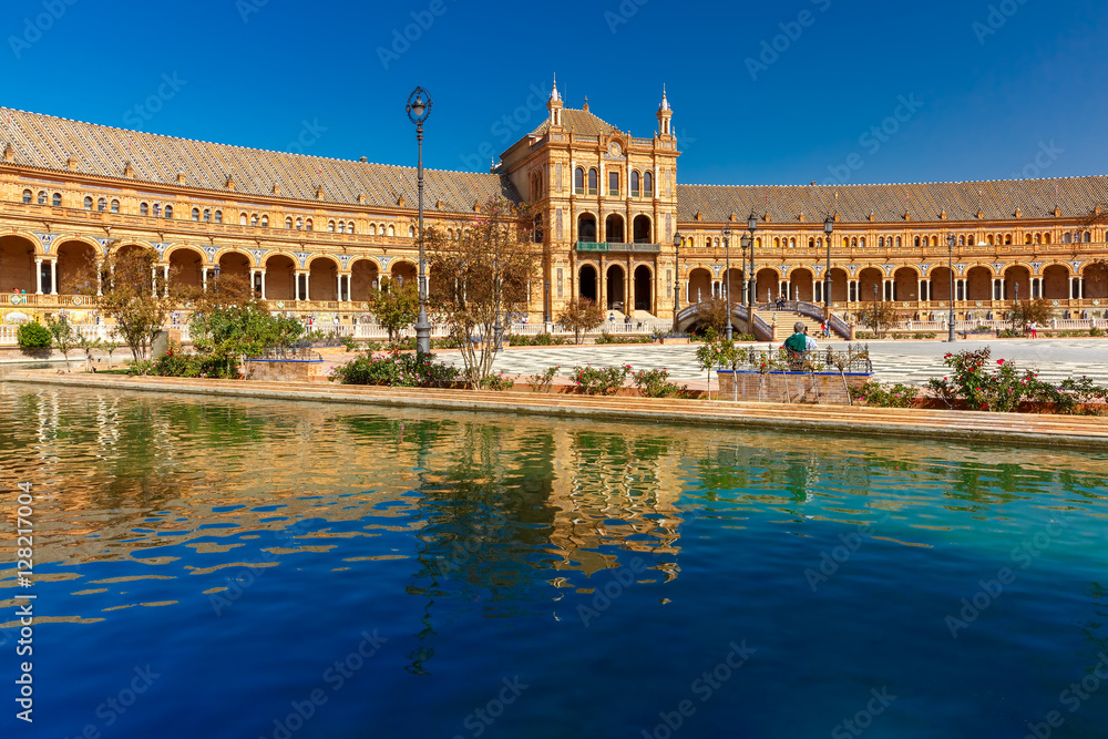 Spain Square or Plaza de Espana in Seville in the sunny summer day, Andalusia, Spain. Flower beds, bridges and channel in the foreground