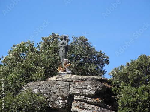 Maria Statue auf Felsen mit Bäumen und Himmel im Hintergrund - Sardinien