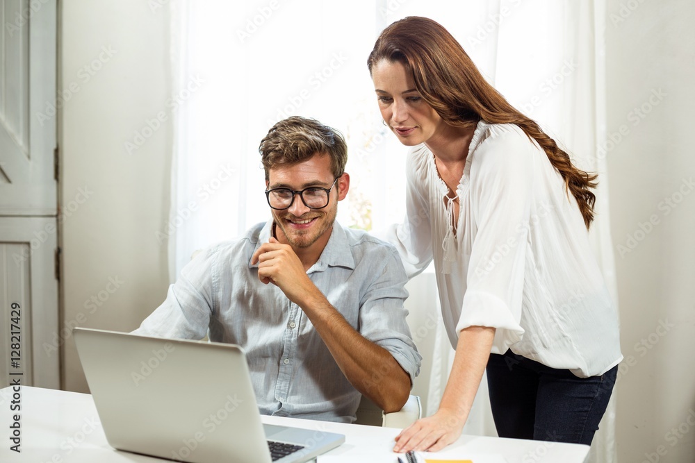 Male and female colleagues using laptop at office Male and female colleagues using laptop at office