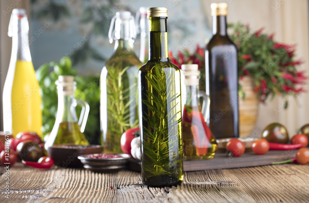 Olive oil and rosemary, chili pepper, many different tomatoes, garlic, red, white, green pepper on old wooden table. Extra virgin olive oil cruets and flavored olive oils with rosemary and chili. Olive oil and rosemary, chili pepper, many different tomatoes, garlic, red, white, green pepper on old wooden table. Extra virgin olive oil cruets and flavored olive oils with rosemary and chili.
