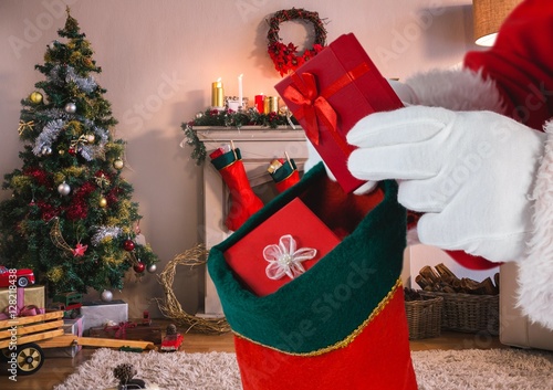 Santa putting gifts in christmas stocking in living room photo