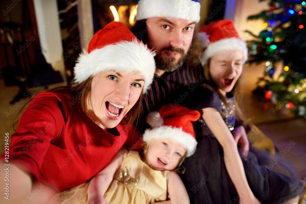 Young happy family of four taking a photo of themselves on Christmas Young happy family of four taking a photo of themselves on Christmas