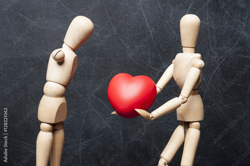 Concept protection of handicapped people. Wooden figure of healthy man gives another physically disabled figure without hands a big red heart as a symbol of love and care. Concept protection of handicapped people. Wooden figure of healthy man gives another physically disabled figure without hands a big red heart as a symbol of love and care.