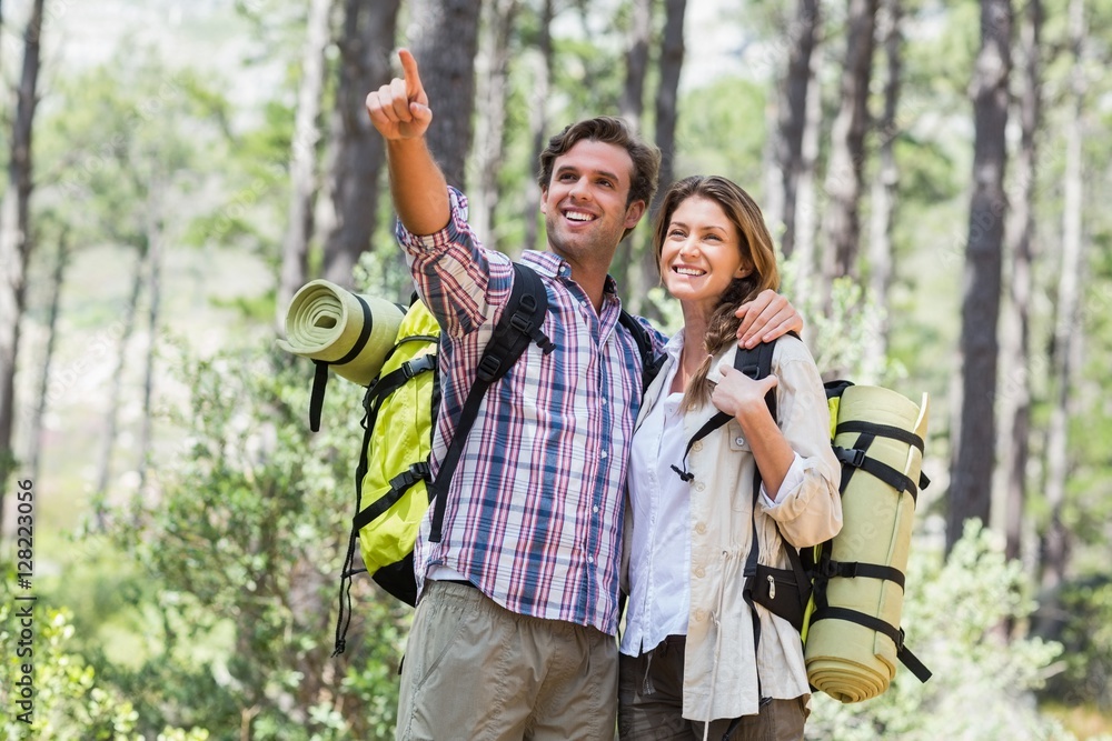 Happy man pointing while standing with partner in forest Happy man pointing while standing with partner in forest
