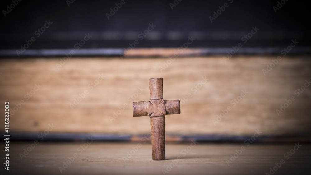 Brown cross on the Bible on a wooden background. Holy book.