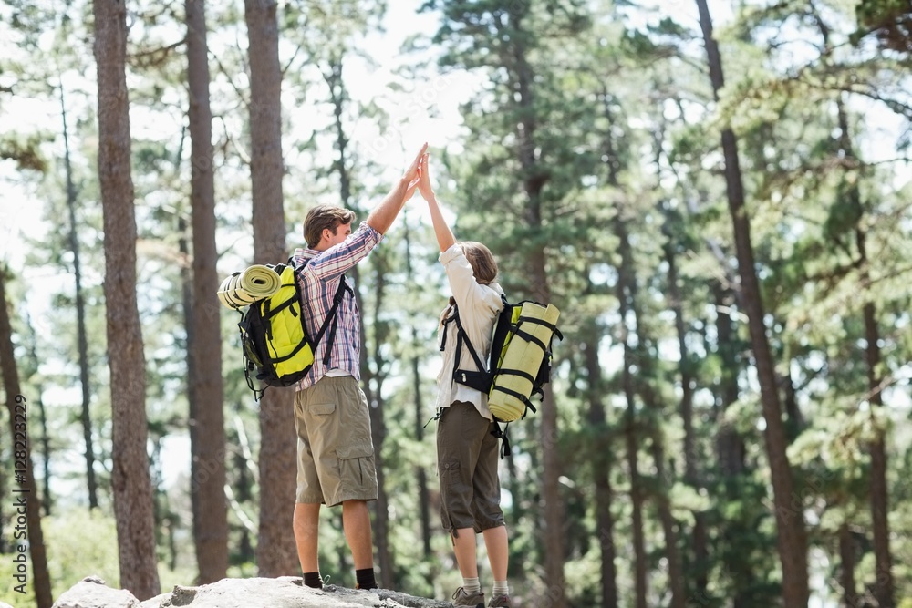 Couple giving high five while standing on rock Couple giving high five while standing on rock