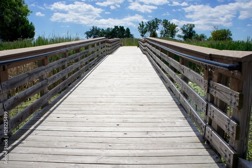 Wooden Walking Path with Blue Sky and White Clouds