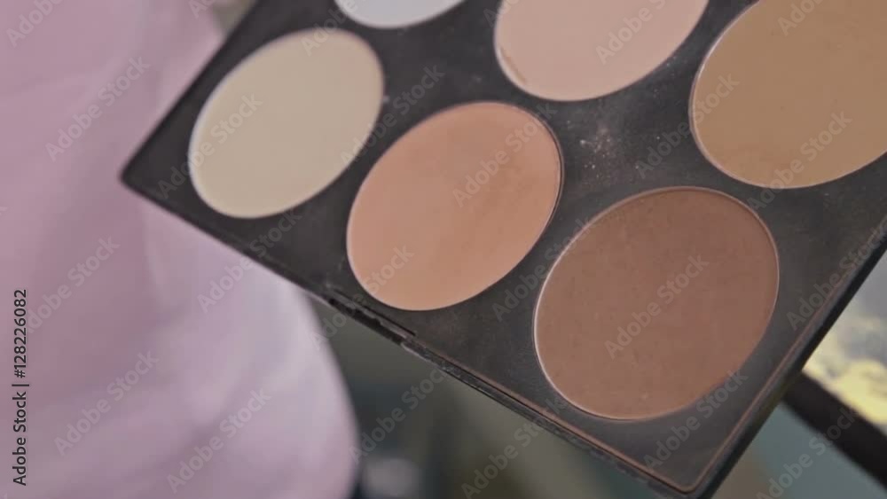 Close up shot. Make-up artist taking blusher from makeup palette in white room. Beauty, makeup and fashion concept Close up shot. Make-up artist taking blusher from makeup palette in white room. Beauty, makeup and fashion concept