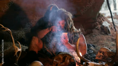 Prehistoric caveman using smartphone photo