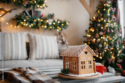 Homemade gingerbread house on background room decorated for Christmas.