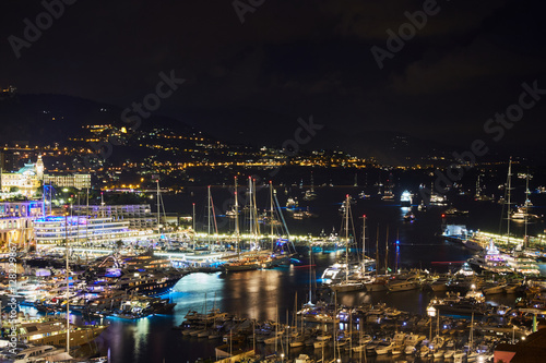 World Fair MYS Monaco Yacht Show at night  Port Hercules  luxury megayachts  many shuttles  party time  boat traffic  long exposure  aerial view  cityscape  night lights  illumination of boat