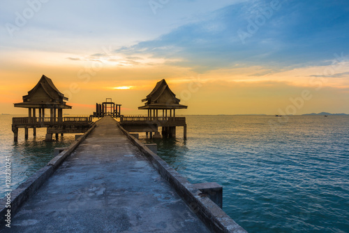 Beauty of sunset skyline over the ocean with walking way leading to temple in the sea photo