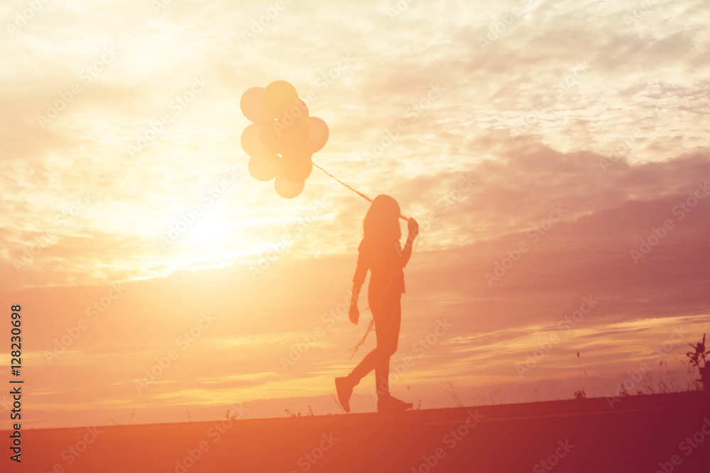 silhouette of young woman holding colorful of balloons with suns