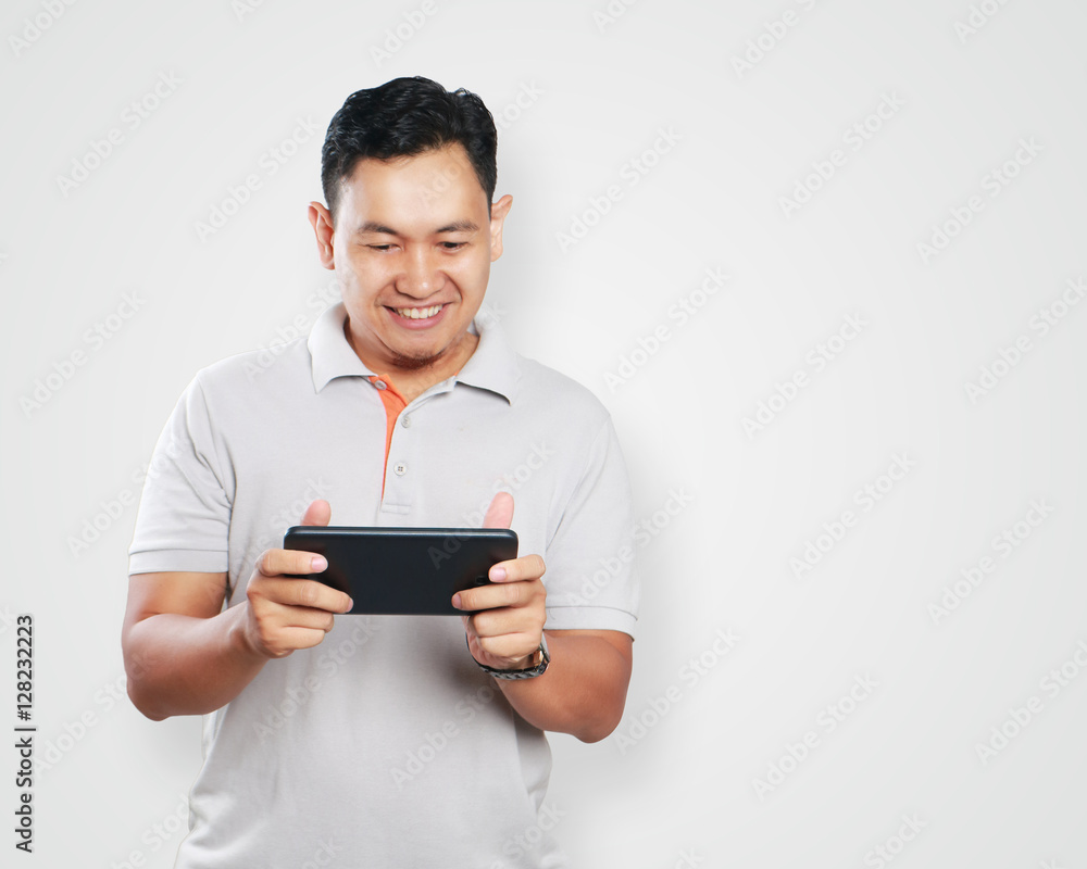 Funny Young Asian Guy Playing Games on Tablet Funny Young Asian Guy Playing Games on Tablet