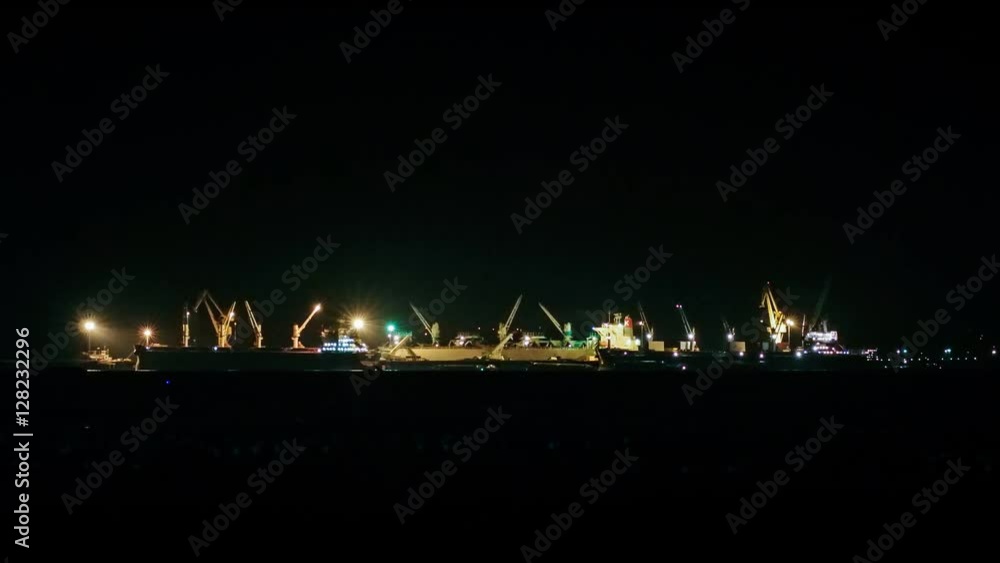 Time lapse of crane working at port with cargo ship in night sea Time lapse of crane working at port with cargo ship in night sea