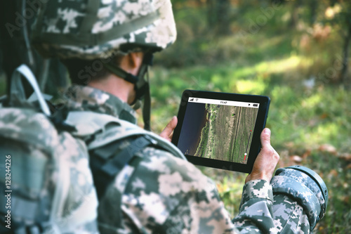 Soldier using map on tablet for orientation at forest