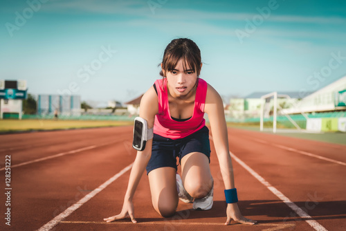 Confident young female athlete in starting position ready to sta