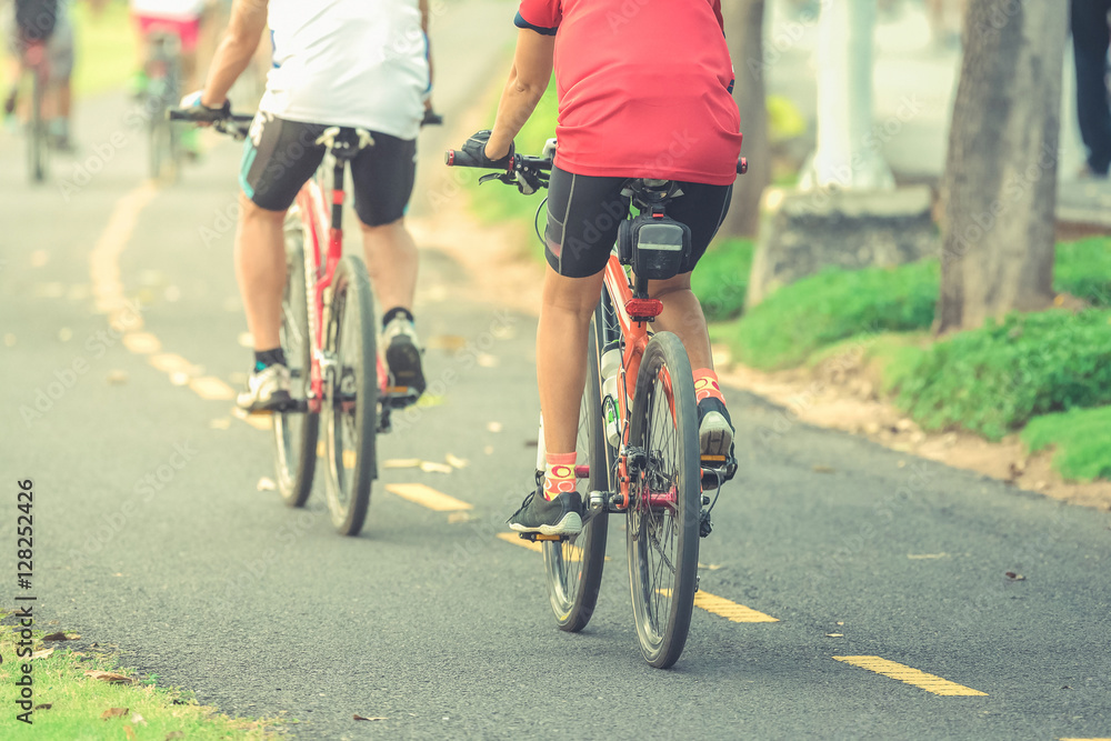 Fototapeta premium Cyclists ride along bike path in park , vintage