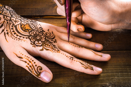 woman mehendi artist painting henna on the hand photo