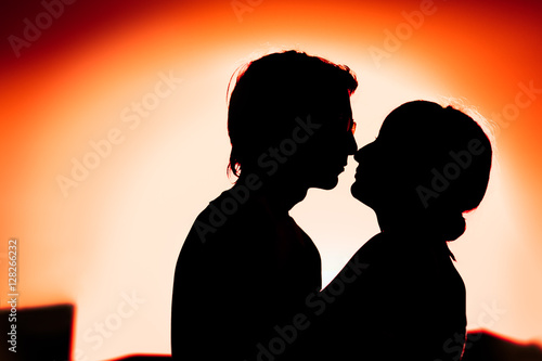 silhouettes of guy and the girl embracing on a background the city