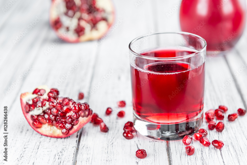 Portion of Pomegranate juice on wooden background (selective foc Portion of Pomegranate juice on wooden background (selective foc