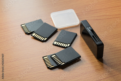 Black memory cards and card reader on wooden background