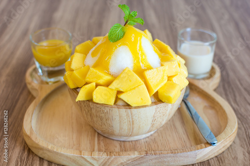 Bingsu ( Korea food) mango served with sweetened condensed milk on table photo