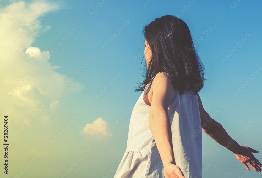 young woman standing and feel cool breeze with blue sky