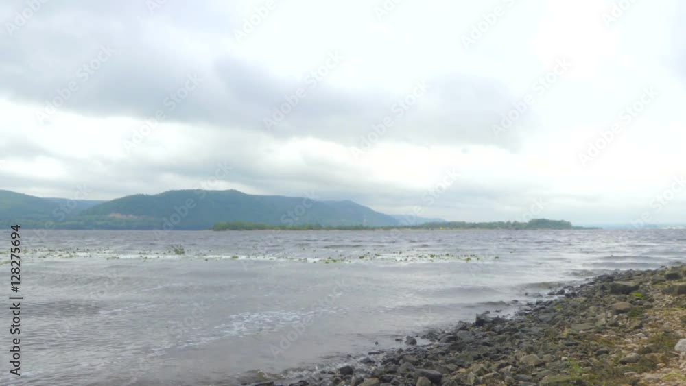 Waves on the shore of the river Volga, Russia. A storm in autumn day. The mountains and islands in the background. Windy weather. The clouds in the sky. Waves on the shore of the river Volga, Russia. A storm in autumn day. The mountains and islands in the background. Windy weather. The clouds in the sky.