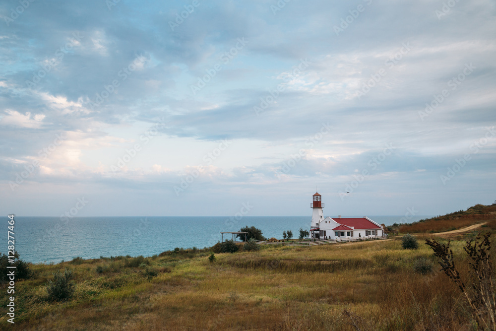 Old white lighthouse on sea coast, summer landscape