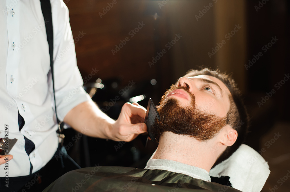 Fototapeta premium Master cuts hair and beard of men in the barbershop