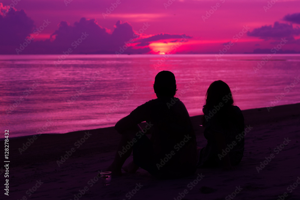Silhouette of the couple enjoying the sunset on the beach
