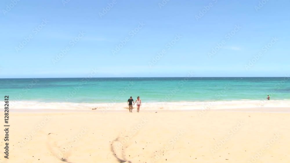 Happy woman and man couple walk together, holding hands on sandy beach. Happy woman and man couple walk together, holding hands on sandy beach.